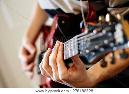 Man Playing Rock On A Red Electric Guitar On A Sunny Day