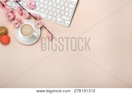 White Cup With Cappuccino, Sakura Flowers, Keyboard On A Pastel Pink Background. Top View.
