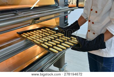 Woman Cooking In The Kitchen, Puts Cakes In The Oven