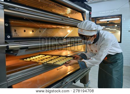 Saigon, Vietnam - Jan 9, 2019. Woman Cooking In The Kitchen, Puts Cakes In The Oven