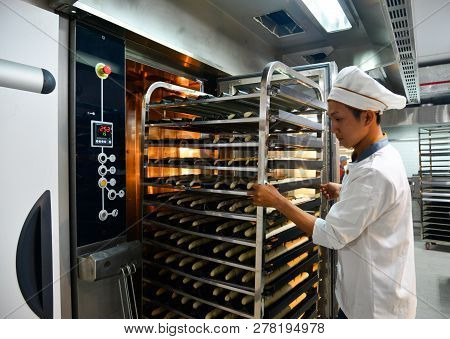 Saigon, Vietnam - Jan 9, 2018. A Man Working With Racks Of Freshly Baked Bread At The Factory In Sai