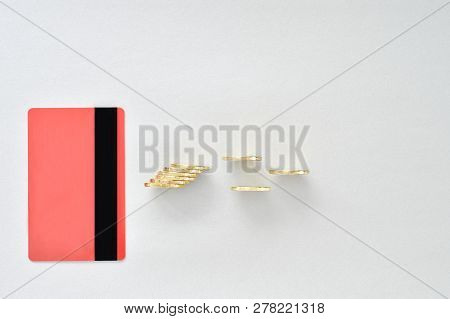 A Bank Card In The Color Of Living Coral With Shiny Yellow Coins, Symbolizing Electronic Payment