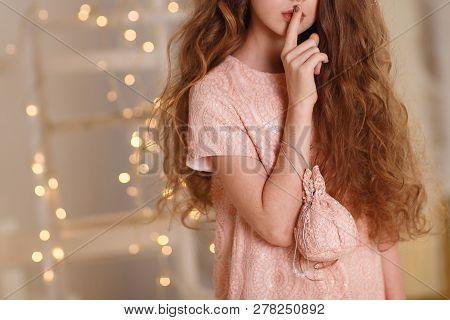 Girl With Lush Hair Index Finger To Lips On The Background Of Garlands