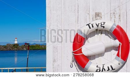 Rescue Ring In Norwegian Harbor And Seascape With Lighthouse At Hovsund Fishing Port, Gimsoya Lofote