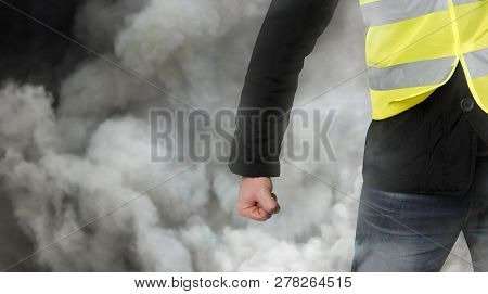 Yellow Vests Protests. Unrecognizable Man Clenched His Fist In Protest In Tear Gas. The Concept Of R