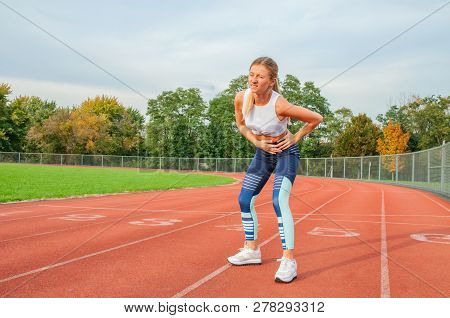 Athletic Woman On Running Track Has Side Cramps During Workout