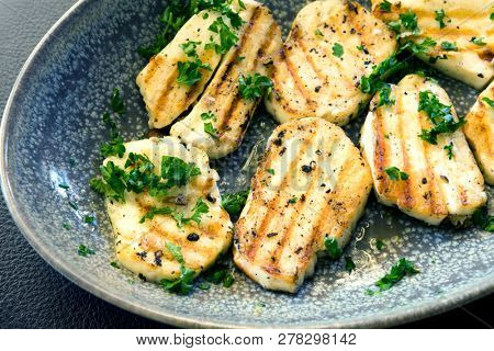 Grilled haloumi cheese in stone serving dish, topped with parsley.
