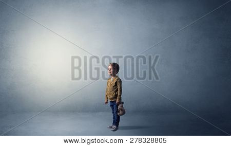 Little waggish kid staying alone in a big empty room with his plush