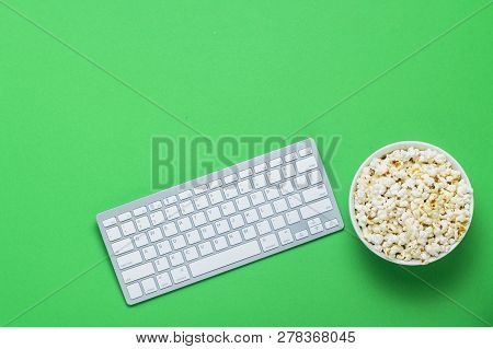 Keyboard And Bowl With Popcorn On A Green Background. The Concept Of Watching Movies, Tv Shows, Show