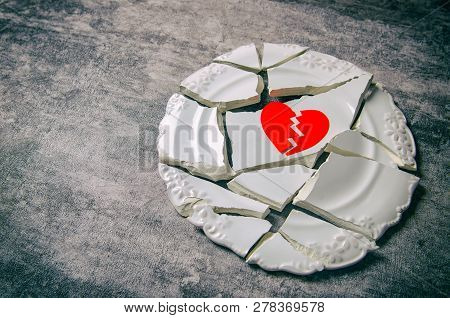 Broken Heart Concept. Divorse, Quarrel. Broken Vintage Porcelain Plate On Old Grey Background. Smith