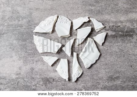 Broken Heart Concept. Divorse, Quarrel. Broken Vintage Porcelain Plate On Old Grey Background. Smith
