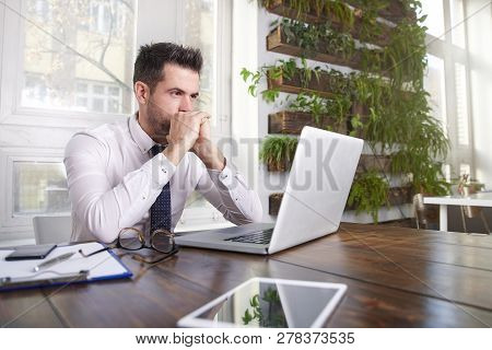 Careworn Businessman Sitting In Front Of Laptop And Working