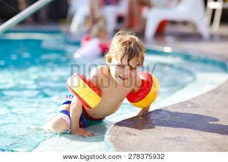 Happy Little Kid Boy Having Fun In An Swimming Pool. Active Happy Child Learning To Swim. With Safe 