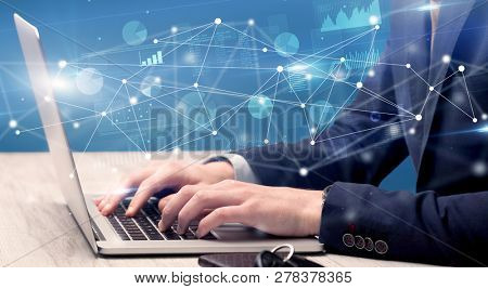 Businessman typing on laptop with linked reports charts grapghs around