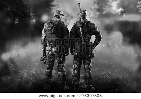 Two Soldiers Of A Special Unit Are Standing In A Smoky Forest.