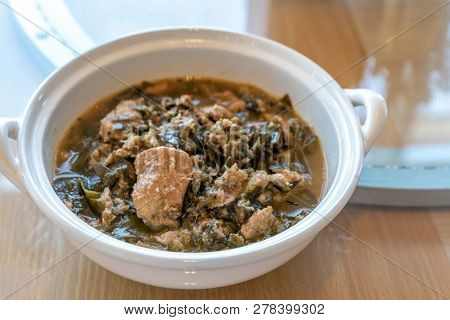 Thai Chamuang pork soup, pork with cowa leaf, thai east traditional food cuisine in white bowl on wooden background