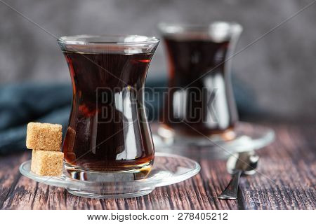 Turkish Glass For Tea Bardak With Cane Sugar On Dark Wooden Table.