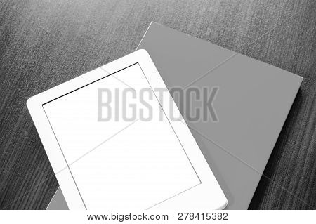 On The Table Is A Portable E-book And Paper Book.
