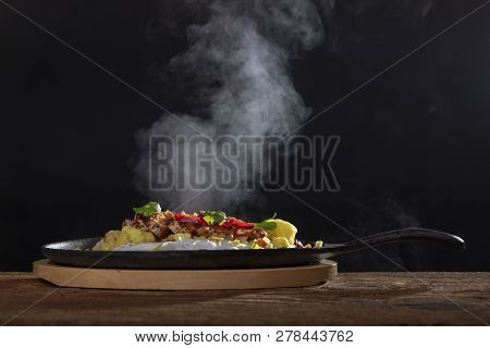 Steaming Hot Sizzler On Wood On Black