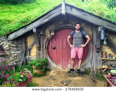 Hobbiton Movie Set, North Island, New Zealand February 17th, 2016:  A Man Standing Outside Of A Hobb