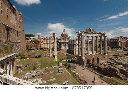 ROME, ITALY - AUGUST 15, 2018: Tourists in the Roman Forum at Temple of Saturn against Arch of Septimius Severus. Historical center of Rome is UNESCO World Heritage site