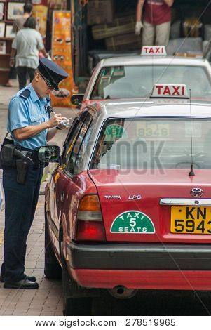 Hong Kong Island, China  - May 12, 2010: A Traffic Cop In Blue Writes A Red Taxi Cab Up For An Infra