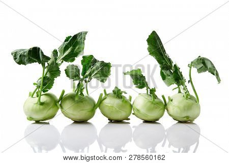 Fresh kohlrabi with leafy stems still attached on white background