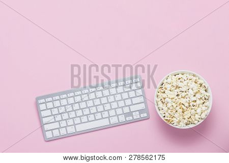 Keyboard And Bowl Of Popcorn On A Pink Background. The Concept Of Watching Movies, Tv Shows And Show