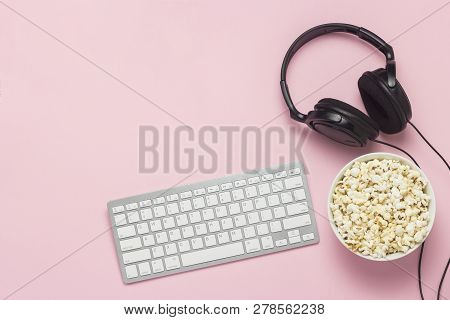 Keyboard, Headphones And A Bowl Of Popcorn On A Pink Background. The Concept Of Watching Movies, Sho