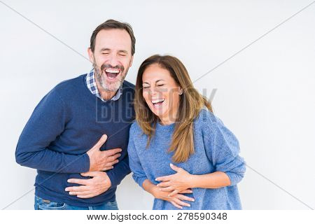Beautiful middle age couple in love over isolated background Smiling and laughing hard out loud because funny crazy joke. Happy expression.