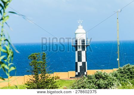 Lighthouse Black And White On Headland Point  Overlooking Windy Blue Ocean For Shipping Marine Night