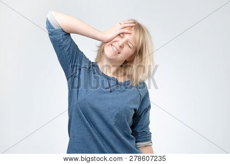 Young Blonde Woman Wearing Blue Pulover Surprised With Hand On Head For Mistake, Remember Error