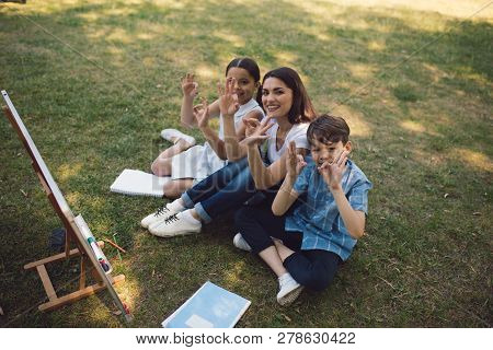 Boy And Girl Wth Teacher In Park. Smiling And Showing Thumds Up. Creative Education Concept.