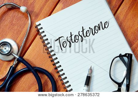 Top View Of Stethoscope,pen,eyeglasses And Notebook Written With Testosterone On Wooden Background.