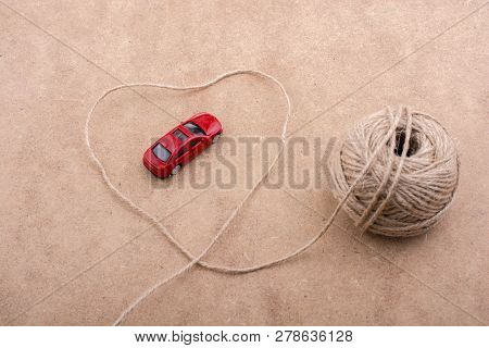 Tred Toy Car And A Spool Of Thread Form A Heart Shape On Background