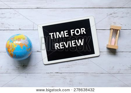 Top View Of Globe,sand Clock And Tablet Written With Time For Review On Wooden Background.
