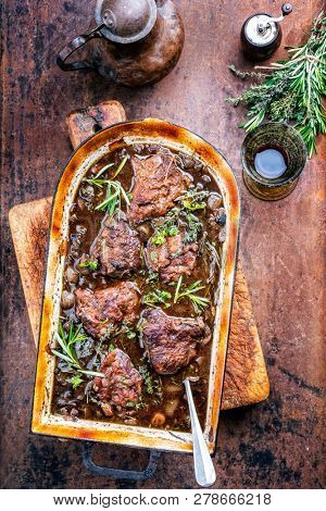 Traditional German braised veal cheeks in brown sauce with mushroom and onions as top view in a stewpot 