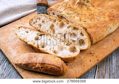 Traditional Italian ciabatta bread with herbs as closeup on a cutting board 
