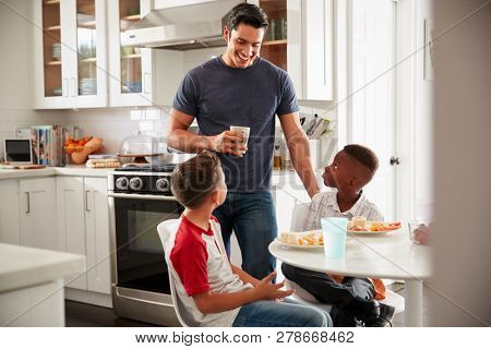 Dad standing in the kitchen talking with his son and a friend, who is over for a playdate