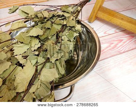 Wooden Floor Of The Sauna With Birch Bunch In Metal Bowl. Finnish Or Russian Traditional Sauna Conce