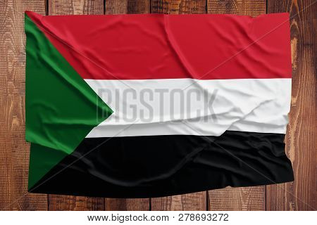 Flag Of Sudan On A Wooden Table Background. Wrinkled Sudanese Flag Top View.