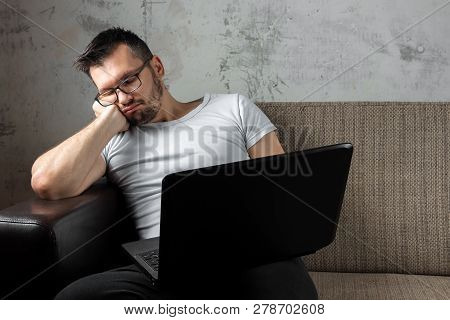 The Guy In The White Shirt Sitting On The Couch, Fell Asleep At Work On A Laptop. The Concept Of Laz