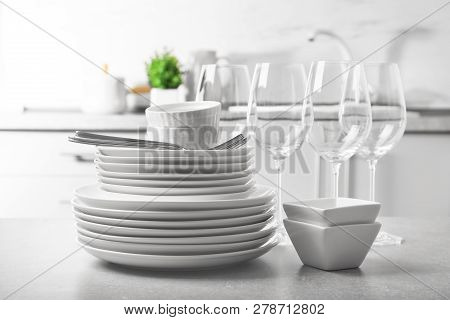 Set Of Clean Dishes And Cutlery On Table In Kitchen