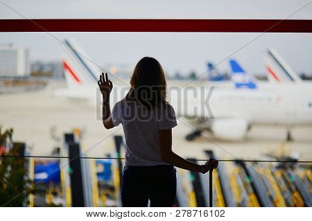 Silhouette Of Young Woman In International Airport, Looking Through The Window At Planes