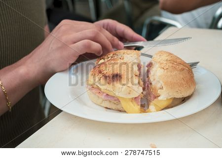 Man Eating Ham And Cheese Sandwich At A Restaurant