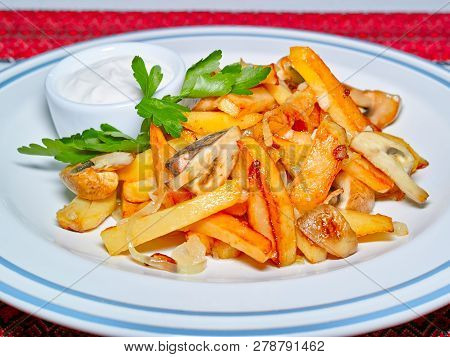 Homemade Fried Potato With Mushrooms And Onion, Served On A Plate With Parsley And Cream Sauce