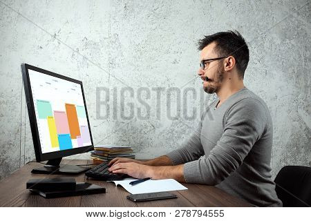 A Man, A Man Sitting At A Table In The Office, Working On A Computer. The Concept Of Office Work. Co