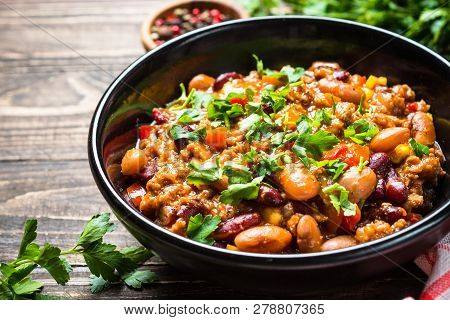 Chili Con Carne From Meat, Beans And Vegetables On Dark Wooden Table. Traditional Mexican Food.