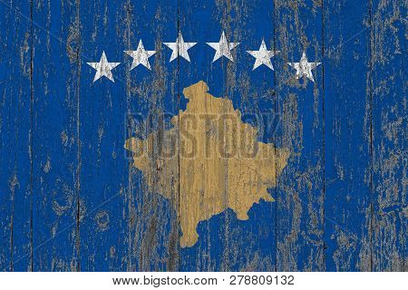 Flag Of Kosovo Painted On Worn Out Wooden Texture Background.