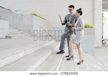 Vietnamse Business Couple Reading Data On Tablet Computer When Walking Up The Stairs